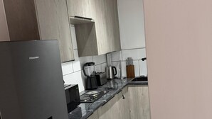 Ett modernt kök med ett kylskåp i rostfritt stål, träskåp, en bänkskiva med en kaffebryggare och en diskho.