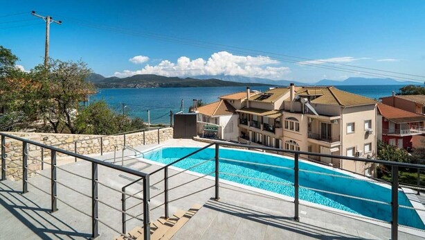 A swimming pool with a view of a coastal town and mountains.