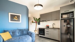 A modern kitchen with grey cabinets, a stainless steel refrigerator, and a coffee maker on the counter.