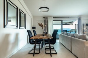 Uma sala de jantar moderna com mesa, cadeiras e vista para o mar.