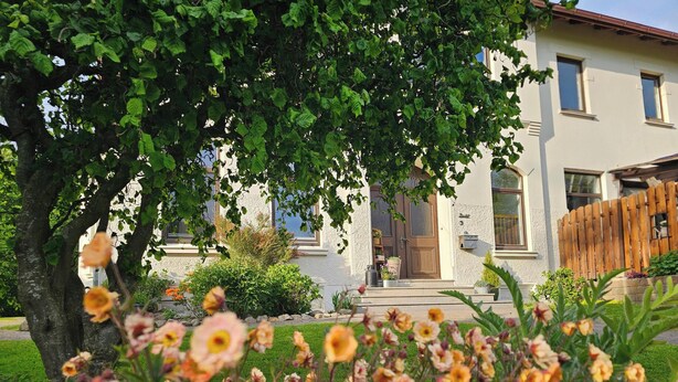 A house with a garden, a tree, and a wooden fence. - Kuhstall Apartment with Shared Terrace, Garden and Wi-Fi (Wurster Nordseeküste)