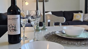 A dining table with a wine bottle, two glasses, a candle, and a bowl. - Kuhstall Apartment with Shared Terrace, Garden and Wi-Fi (Wurster Nordseeküste)
