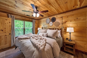 Ein Schlafzimmer einer Holzhütte mit Bett, Deckenventilator und Wanddekoration.