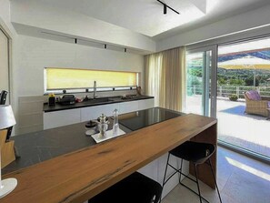A modern kitchen with a large island, a window with curtains, and a view of the outdoors. - Mediterranean villa with panoramic infinity pool (Castellammare del Golfo)