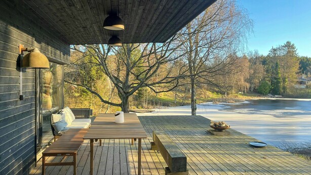Un pontile in legno con tavolo e panche, con vista su un corpo d'acqua e alberi.