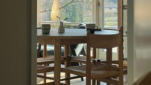 Zona pranzo con tavolo, sedie, lampadario e vista attraverso una finestra.