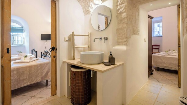 Ein Badezimmer mit rundem Spiegel, Waschbecken, Toilette und Duschbereich.