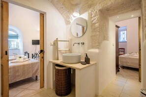 A bathroom with a round mirror, a sink, a toilet, and a shower area. - 19th-century trulli complex among vineyards (Martina Franca)