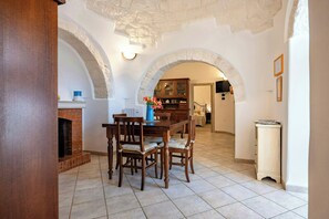 A dining area with a brick fireplace, wooden dining table, and chairs. - 19th-century trulli complex among vineyards (Martina Franca)