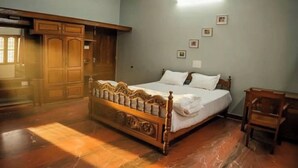 A bedroom with a wooden bed, a wooden wardrobe, and a small wooden chair.
