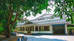A two-story building with a covered porch and a paved entrance.