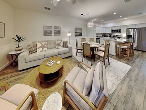 A modern living room with a sofa, coffee table, and dining area. - The Flip Flop Flat | Updated, Pet Friendly, & Community Pool (Port Aransas)