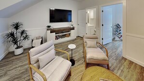 A modern living room with a sofa, chairs, a coffee table, a TV, and a bookshelf. - The Flip Flop Flat | Updated, Pet Friendly, & Community Pool (Port Aransas)