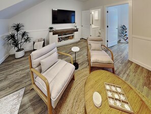A modern living room with a sofa, chairs, a coffee table, a TV, and a bookshelf. - The Flip Flop Flat | Updated, Pet Friendly, & Community Pool (Port Aransas)