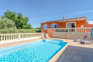 Ein Schwimmbecken mit einer Steinmauer und einem Gebäude mit blauen Fensterläden.