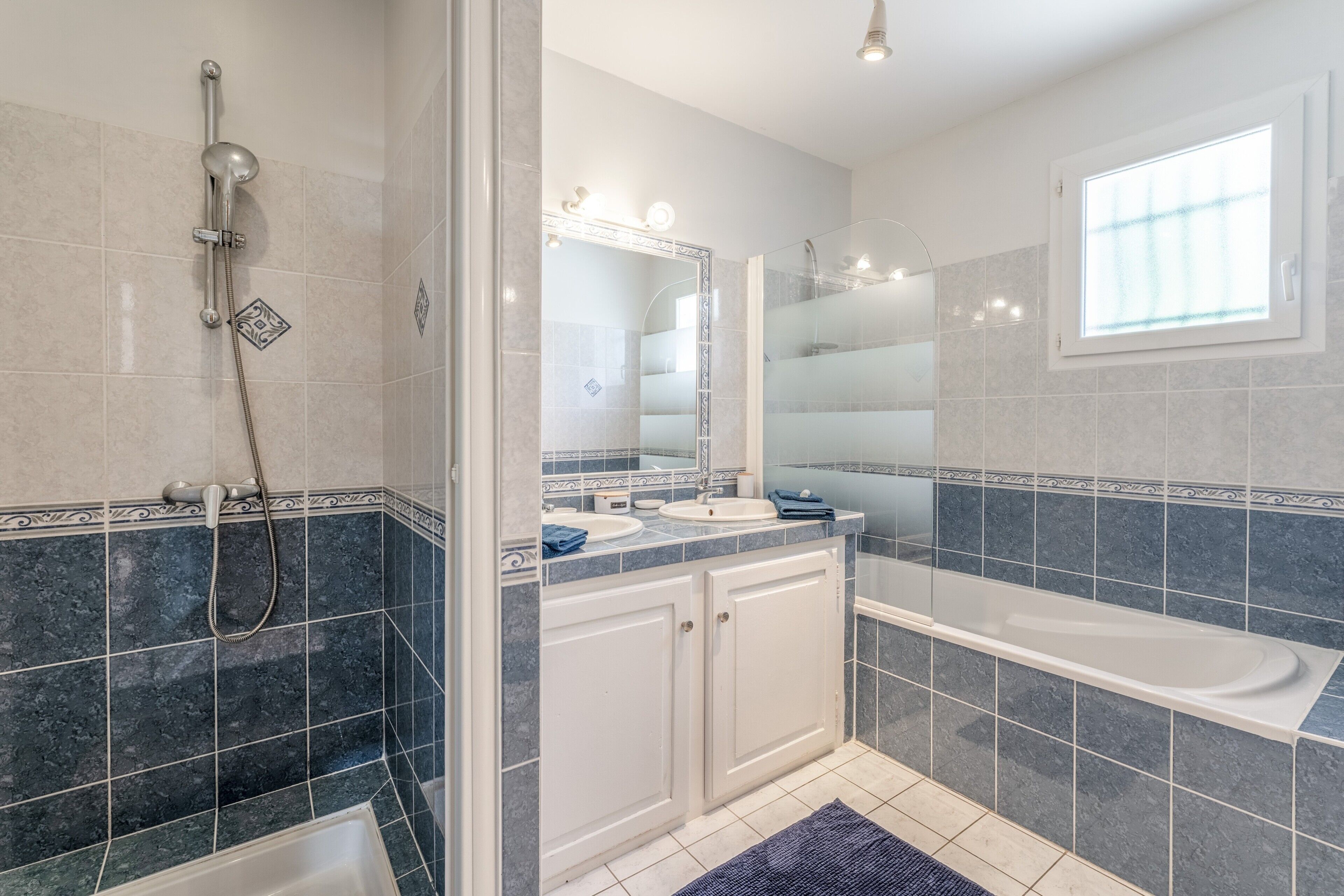 Un bany modern amb un envàs de dutxa de vidre, una banyera i un lavabo amb mirall.