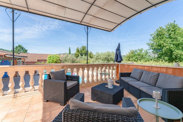 Une terrasse extérieure aménagée avec des meubles en osier, une petite table et une vue sur le paysage environnant.