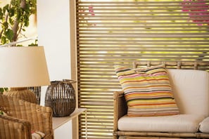 A wicker chair with a striped pillow, a wicker lamp, and a wicker basket on a white table. - Villa with terraces on Castellammare Gulf (Alcamo)