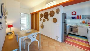 A modern kitchen with a stove, oven, and refrigerator. There is a dining table with chairs and a lamp. - Villa with terraces on Castellammare Gulf (Alcamo)