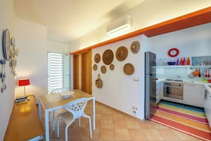 A modern kitchen with a stove, oven, and refrigerator. There is a dining table with chairs and a lamp. - Villa with terraces on Castellammare Gulf (Alcamo)