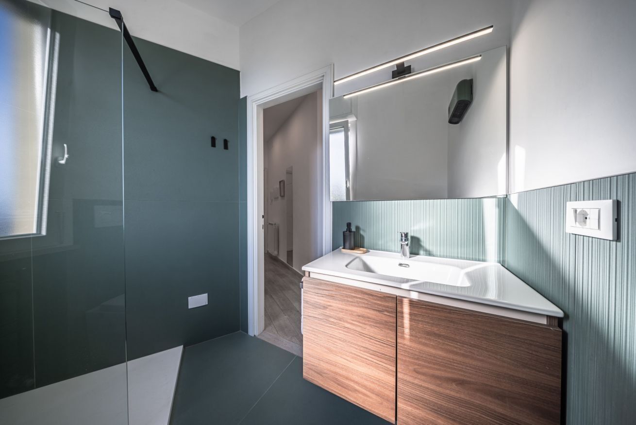 Een moderne badkamer met een grote spiegel, een wastafel en een douchehoek.