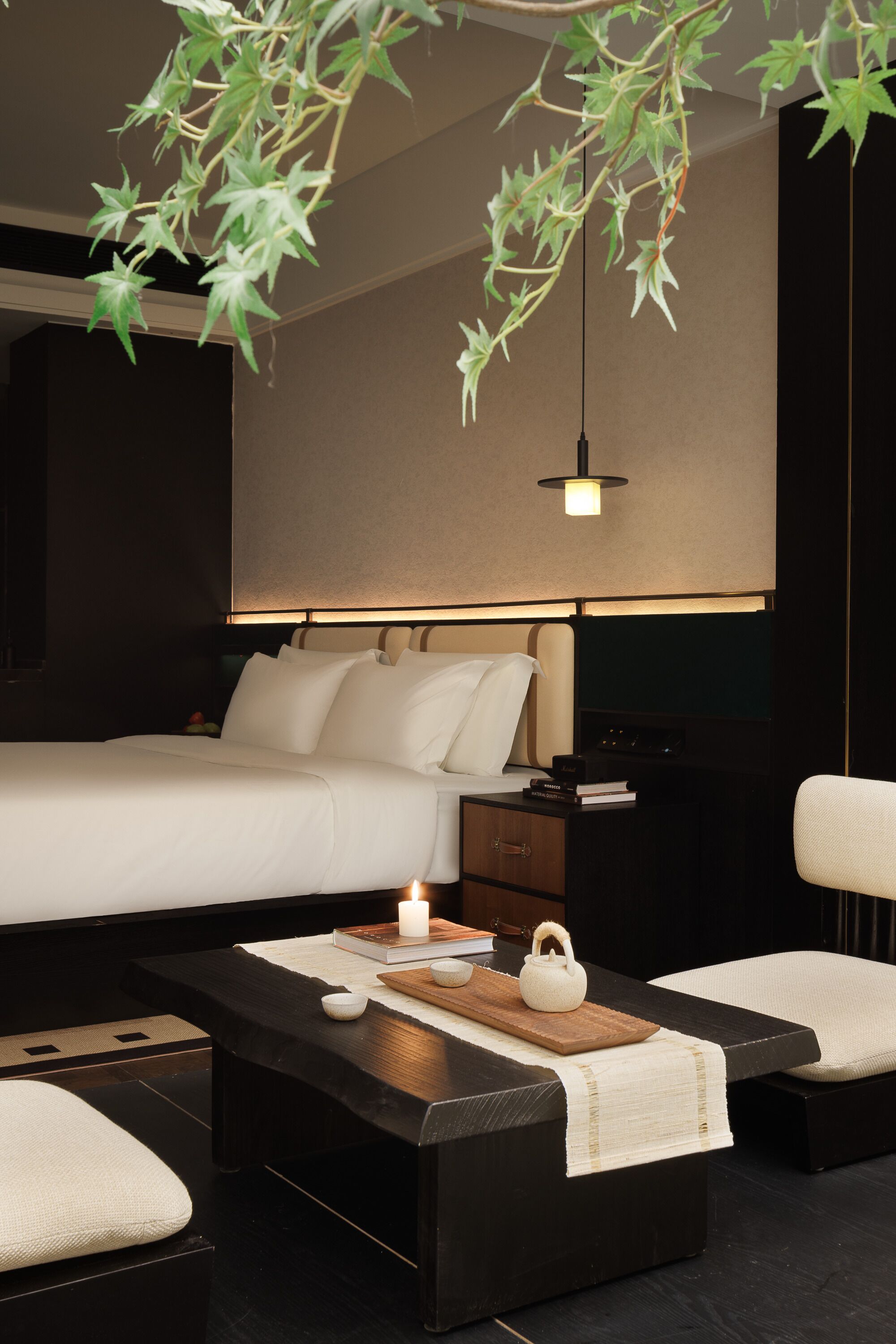 Una habitación de hotel moderna con cama, mesita de noche y una zona de estar con una mesa de centro.