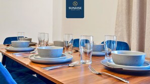 A dining table set with plates, bowls, glasses, and cutlery, with a logo on the wall. - Spacious 4BR City Centre Apartment Dundee (Dundee)