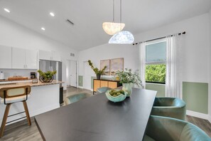 A modern kitchen with white cabinets, a dark countertop, and a central island with seating.