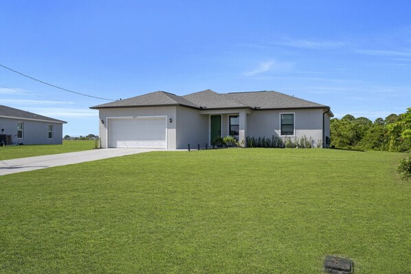 A single-story house with a garage, a front lawn, and a clear sky.