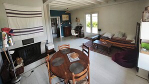 Amplia sala de estar con chimenea, una mesa de comedor con sillas, un sofá y una cocina al fondo.