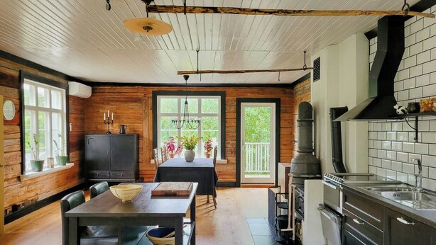 A rustic kitchen with wooden walls, a dining table, and a large window.