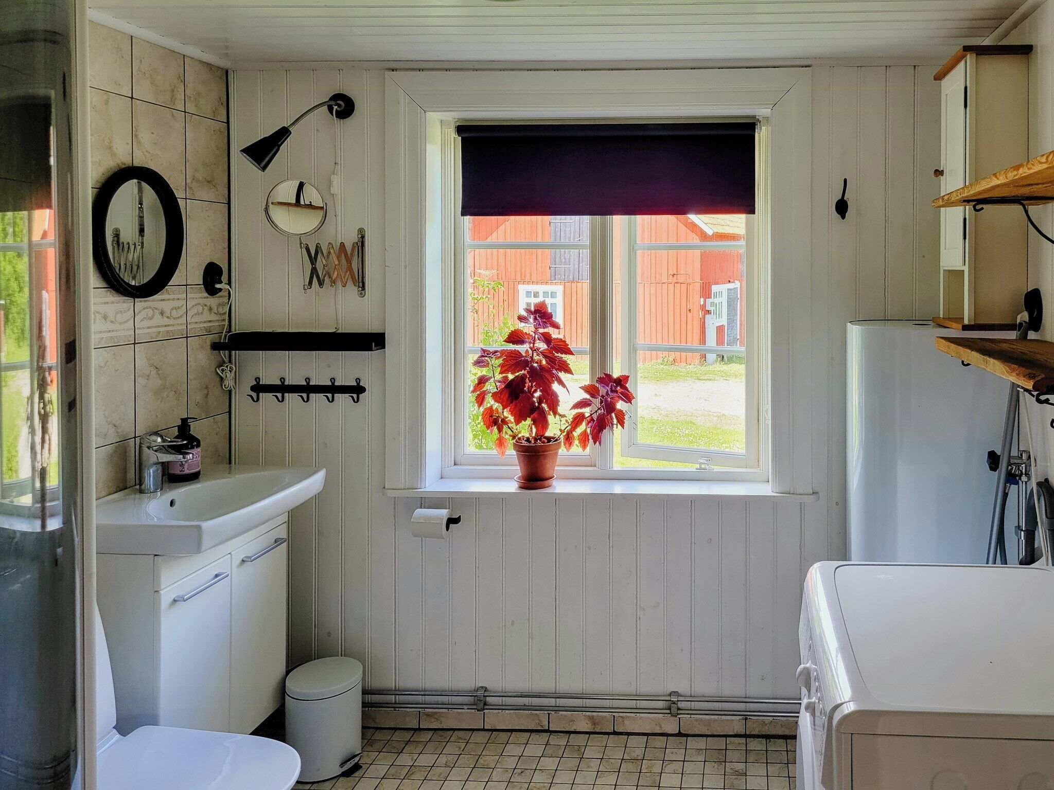 Un baño pequeño con lavamanos, inodoro y ventana con vista a un patio trasero.