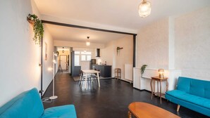 A spacious living area with a dining table, blue sofas, and a kitchen in the background. - Comfortable 2BR Apartment - Central Antwerp (Antwerp)