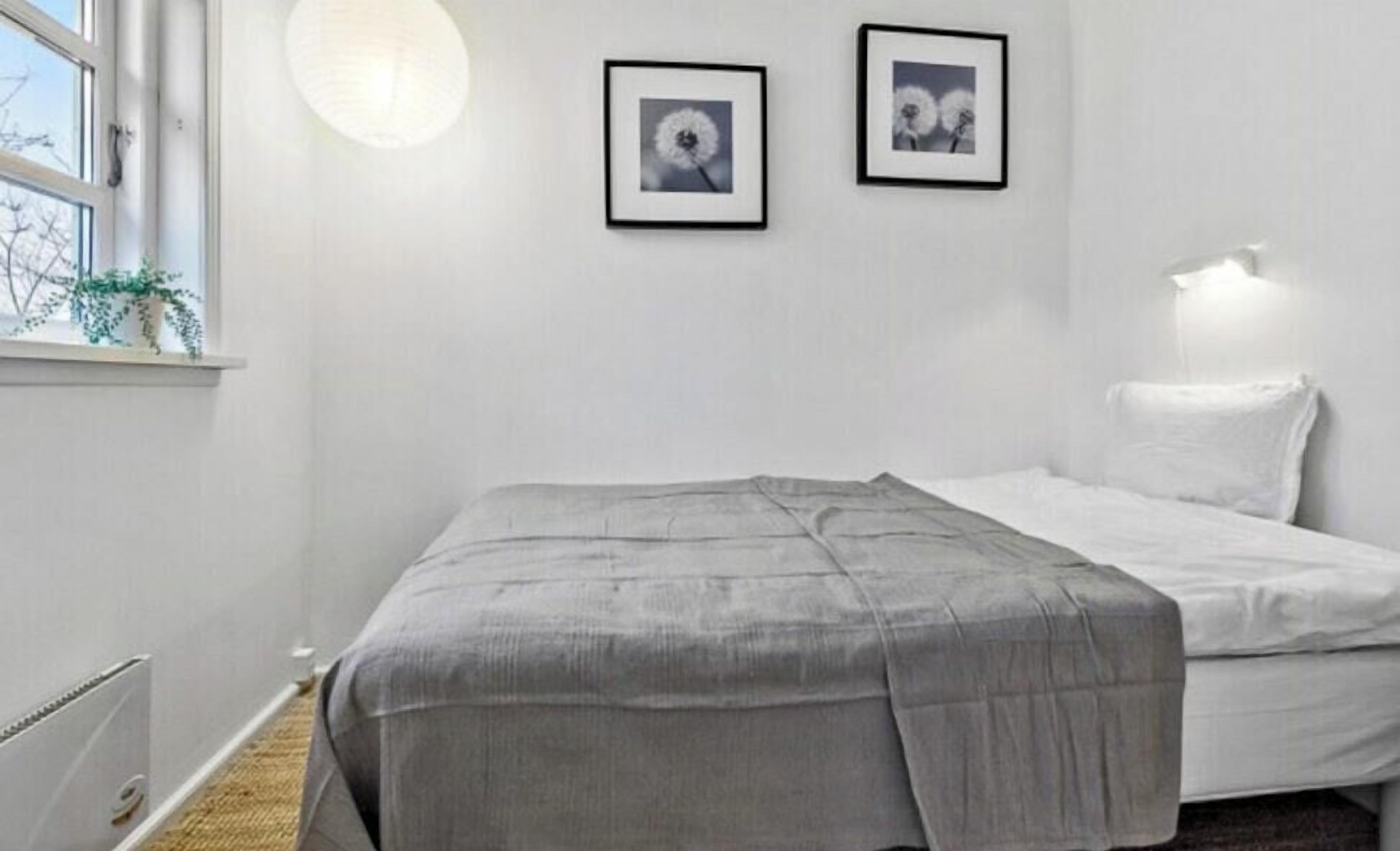 A bedroom with a bed, a window, and two framed pictures on the wall.