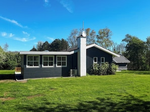 Ein zweistöckiges Haus mit Schornstein, Satellitenschüssel und gepflegtem Rasen.