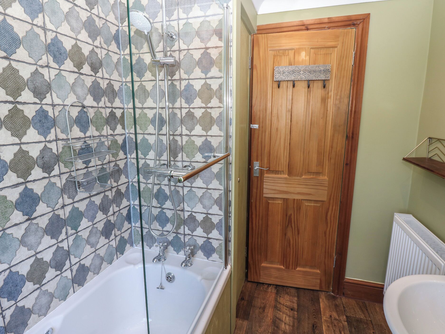 A bathroom with a shower, a wooden door, and a radiator.