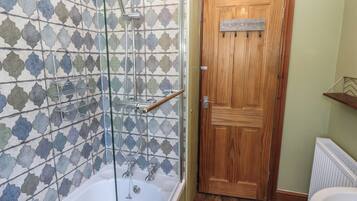 A bathroom with a shower, a wooden door, and a radiator.