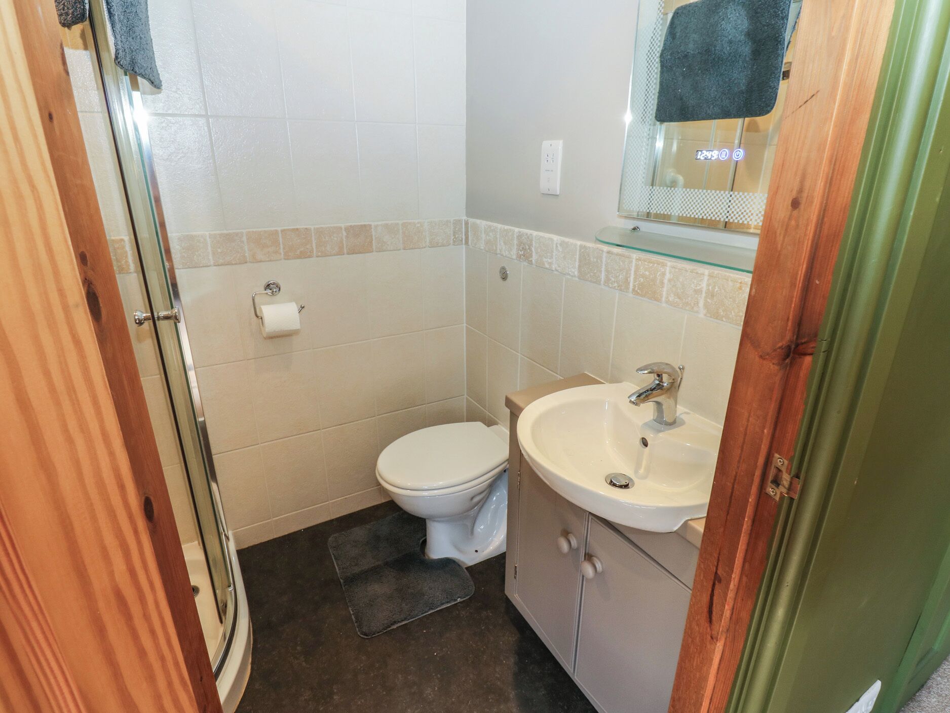 A small bathroom with a toilet, sink, and glass shower enclosure.