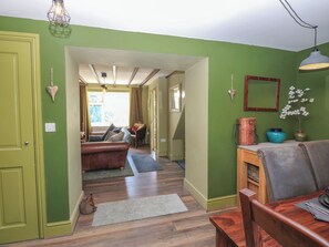 A hallway with a green door, a brown sofa, and a wooden table. - Banklands (Barnard Castle)