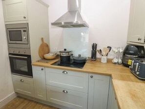A compact kitchen with a microwave, oven, stove, and a coffee maker. - Banklands (Barnard Castle)