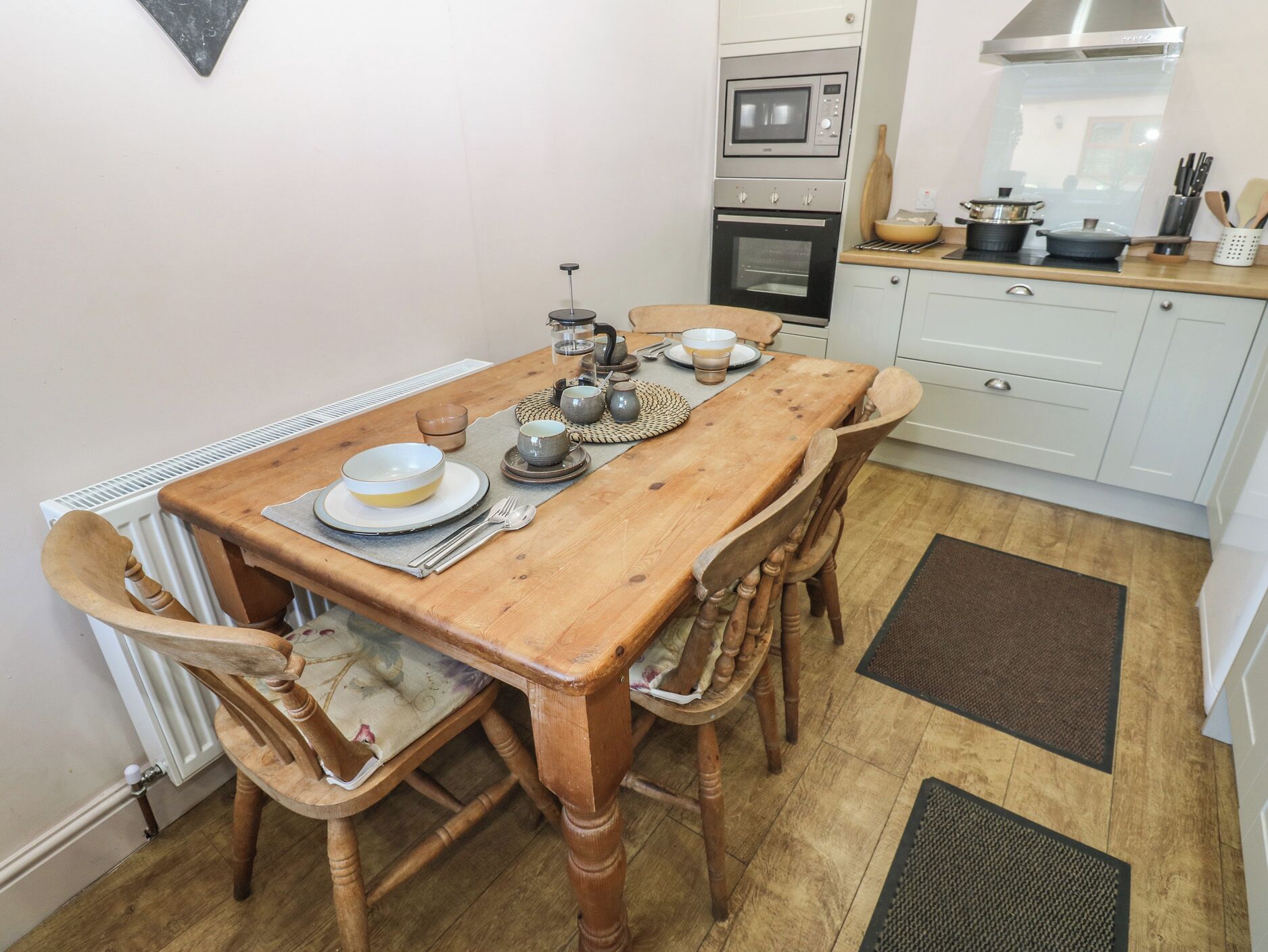 Una mesa de madera con sillas, una cocina con estufa y horno, y un radiador.