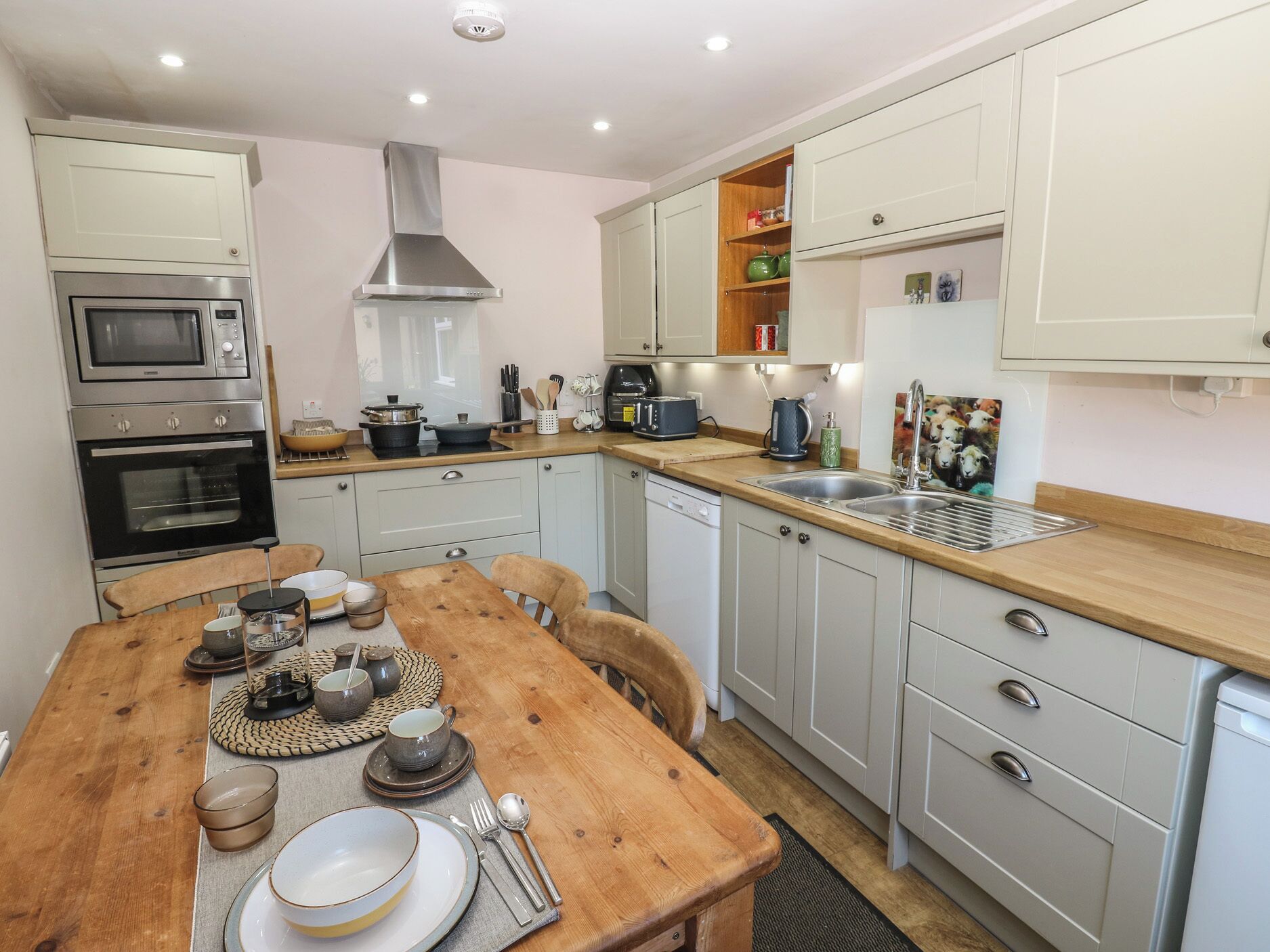 A compact kitchen with a wooden dining table, built-in appliances, and a small island with a sink.