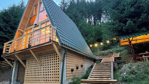 Une cabane en bois avec un toit en pente, un balcon et un escalier menant à une terrasse.