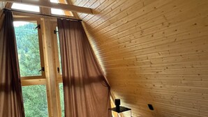 Un intérieur en bois avec un lit, des rideaux et une fenêtre.