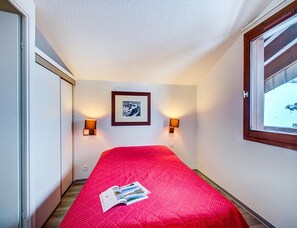 Ein Hotelzimmer mit einem Bett, zwei Wandlampen, einem gerahmten Bild und einem Fenster.
