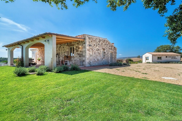 A stone building with a covered patio, surrounded by a well-maintained lawn.