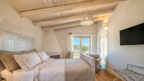 A bedroom with a bed, a hanging light fixture, a window, and a TV mounted on the wall. - Luxury villa with heated pool in a vineyard (Mores)