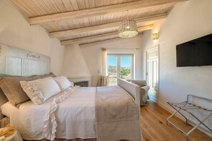 Une chambre à coucher avec un lit, un luminaire suspendu, une fenêtre et un téléviseur fixé au mur.