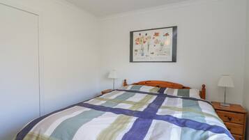 A bedroom with a bed, a nightstand, a lamp, and a framed picture on the wall.