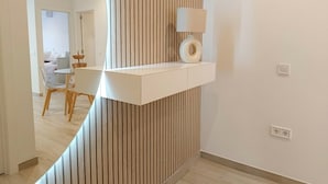 Un intérieur moderne avec une console blanche, une lampe et un mur d’accent en bois.